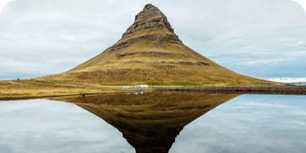 Small hill with it's reflection is shown on the water